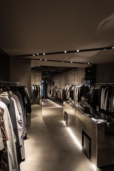 an empty clothing store with clothes on racks and lights hanging from the ceiling in front of them