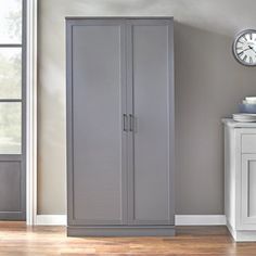 a room with a clock on the wall and a gray cabinet in front of it