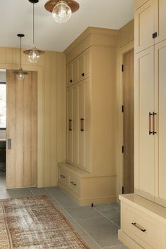 an empty room with beige cabinets and a rug on the floor in front of it