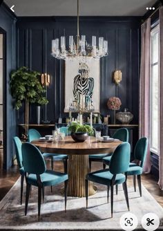 a dining room with blue chairs and a chandelier hanging from the ceiling over a round wooden table