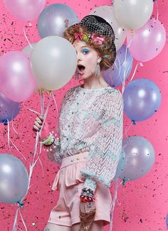 a woman in pink is holding balloons and posing for the camera with her mouth open