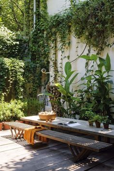 a wooden table sitting on top of a wooden floor next to a lush green wall