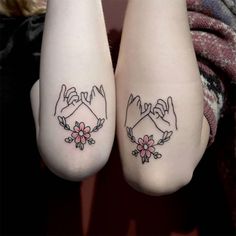 two people with matching tattoos on their feet are holding hands and flowers in the middle