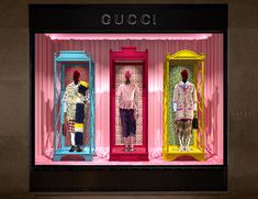 three mannequins dressed in colorful clothing on display inside a store front window