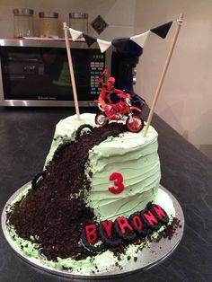 a motorcycle themed birthday cake with dirt on the bottom and 3 byrom written on it