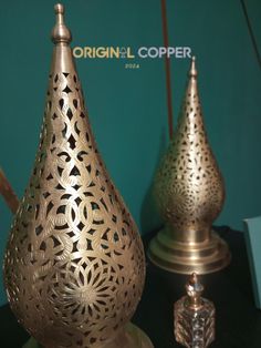 two ornate brass vases sitting on top of a table