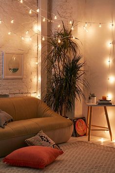 a living room with some lights on the wall and a brown couch next to a potted plant