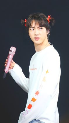 a young man holding a pink object in his right hand and looking at the camera