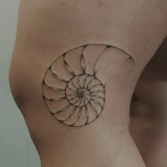 a woman's stomach with a tattoo design on the side of her body, which is shaped like a nautiron shell