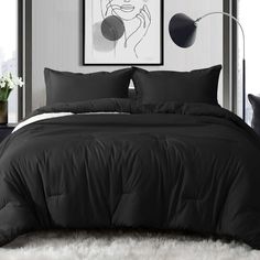 a bed with black comforter and pillows in a room next to a painting on the wall