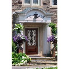 an entrance to a home with flowers and potted plants on the front steps outside