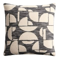 a black and white pillow with geometric shapes on the front, along with an off - white background