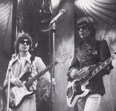 an old photo of two men playing guitars in front of microphones and stage lights