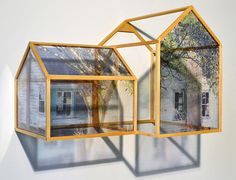 an image of a house made out of glass and wood in front of a white wall