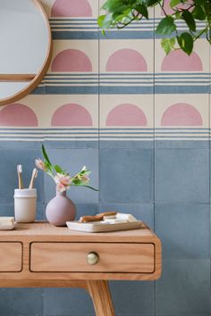 a wooden table topped with a vase filled with flowers next to a mirror and brush