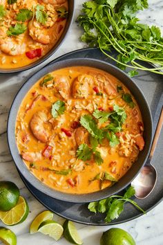 two bowls of shrimp and rice soup with limes on the side