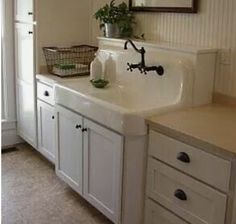 a white kitchen sink sitting under a mirror next to a cabinet with drawers and cupboards