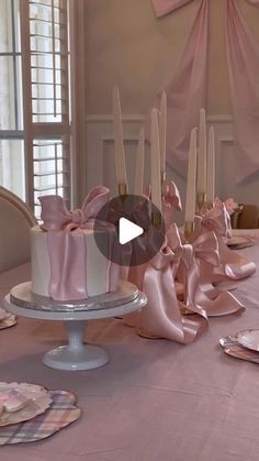 a table topped with a white cake covered in pink ribbon