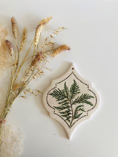 a ceramic ornament with a plant on it next to some dried flowers and grass