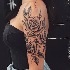 a woman's arm with roses and leaves on her shoulder, in black and white