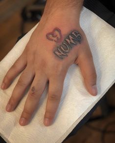 a person's hand with a tattoo on it that says mom and two hearts