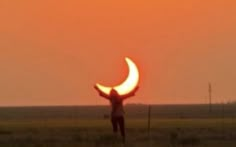 a man standing in the middle of a field with his hands up to the sun