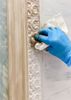 a person in blue gloves and rubber gloves painting a wall with white paint on it