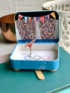 an olympic figure is in a blue box on a table with spoons and forks