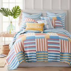 a bed with blue, orange and yellow striped bedspread on top of it