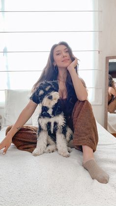 a woman sitting on top of a bed next to a dog