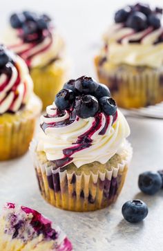 blueberry cupcakes with white frosting and fresh berries