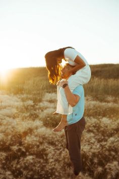 a man carrying a woman on his back in the middle of a field at sunset