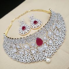 "Handmade Indian Jewelry, best to wear for traditional ceremonies or Indian wedding. This bridal jewelry has ethnic finish. It has very high quality ADs with ruby It is a Bollywood style one gram jewelry. Handmade Indian Jewelry item * Necklace Set is a combo of Necklace & Stud Earrings * Necklace is adjustable with adjustable back chain/ Dori/ Cord * Earring Length: 2\", Earring Width: 1.0\" * Choker : Main design 8 inches. Center 2.5 inches * Gold Color is gold tone which has a bright gold Round Ruby Jewelry With Tilla Details, Diwali Ruby Jewelry Set With Intricate Design, Silver Ruby Jewelry Sets For Festivals, Traditional Ruby Jewelry Sets With Intricate Design, Traditional Red Diamond Bridal Necklace, Festive Heavy Cubic Zirconia Necklace, Traditional Round American Diamond Necklace, Heavy Ruby Jewelry Sets For Wedding, Traditional Kundan Necklace With Elegant Design In Cubic Zirconia