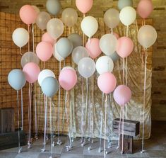 a bunch of balloons that are hanging from the ceiling in front of a wooden wall