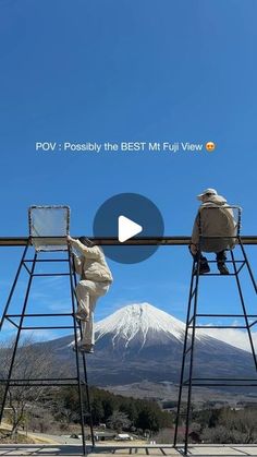 two people sitting on top of metal chairs in front of a mountain with snow capped mountains