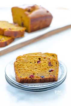 a loaf of fruit bread sitting on top of a plate next to slices of cake