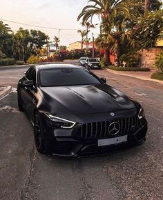 a black sports car parked on the side of the road in front of some palm trees