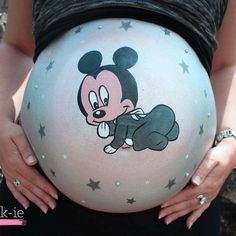 a pregnant woman wearing mickey mouse painted on her belly with stars around her waist and hands