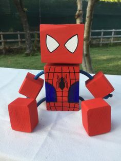 a lego spider man sitting on top of a table next to some red cubes