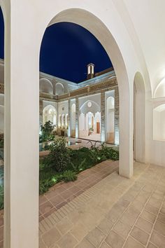 an outdoor courtyard with arches and plants at night