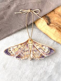 a moth hanging from a string on top of a piece of wood next to a pillow