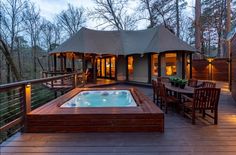 a hot tub sitting on top of a wooden deck next to a gazebo and trees