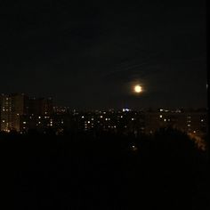 the full moon shines brightly in the dark night sky over cityscapes and trees