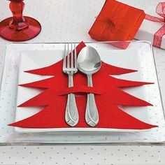 a white plate topped with silverware next to a red christmas tree napkin and fork