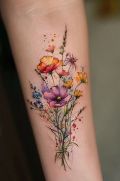 a colorful flower tattoo on the arm with watercolor paint splatters and flowers