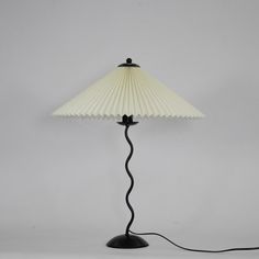 a lamp that is on top of a white surface with a black cord attached to it