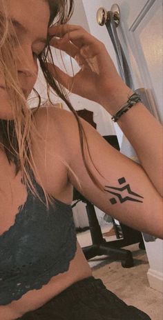 a woman with a tattoo on her arm looking at herself in front of a mirror