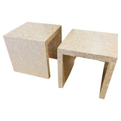 two white marble side tables with one sitting on the other, both facing each other