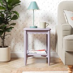 a small table with a lamp on it next to a chair and potted plant