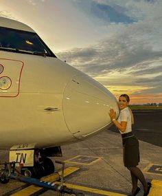 a woman standing next to an airplane on the tarmac